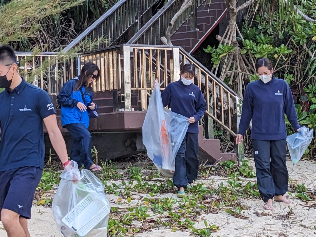 数名の人々が砂浜でゴミ拾いをしている様子